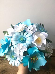 a vase filled with paper flowers on top of a wooden table