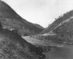 an old black and white photo of a river in the middle of a mountain range