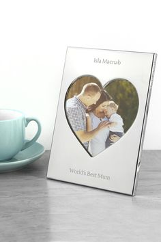 a heart shaped photo frame with the words world's best mum on it next to a cup and saucer