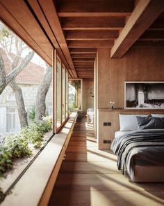 a bedroom with wooden walls and flooring next to a large window that overlooks trees