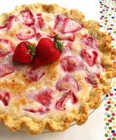 a pie with strawberries on top sitting on a table