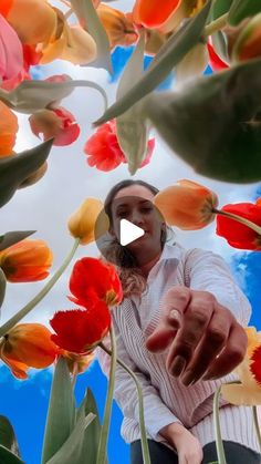 a woman is pointing at flowers in the sky