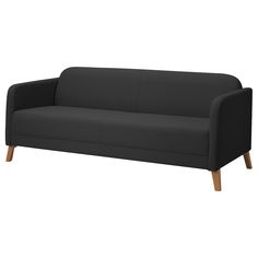 a black couch sitting on top of a white floor next to a wooden leg chair