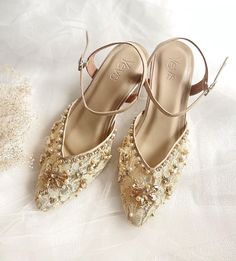 a pair of shoes with gold sequins on them sitting on a white cloth