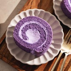 two white plates with purple cake on them and one has a fork next to it