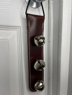 a door handle is attached to a white door with brown leather and silver knobs