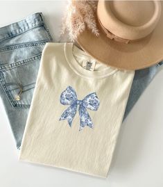 So cute!  EMBROIDERED Toile EMBROIDERED Couquette Bow shirt 🎀 PREMIUM VINTAGE style Comfort Colors Embroidered Tee! * 100% ring-spun cotton * Fabric weight: 6.1 oz/yd² (206.8 g/m²) * Garment-dyed * Relaxed fit * 7/8″ double-needle topstitched collar * Twill-taped neck and shoulders for extra durability * Double-needle armhole, sleeve, and bottom hems * Blank product sourced from Honduras This product is made especially for you as soon as you place an order, which is why it takes us a bit longer Bow Shirt, Blue Toile, Bow Shirts, Embroidered Tee, Honduras, Vintage Stil, Gift For Mom, Comfort Colors, Style Vintage