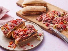 two plates with sandwiches on them next to a cutting board