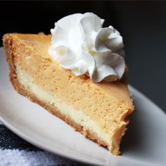 a piece of cheesecake with whipped cream on top is sitting on a white plate