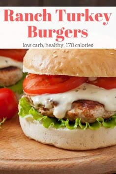 a hamburger with lettuce, tomatoes and turkey on it sitting on a cutting board