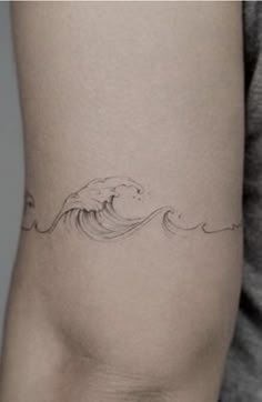 a woman's arm with a wave tattoo on the left side of her thigh