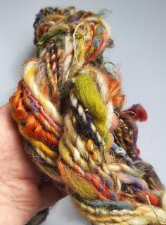 someone is holding some colorful yarn in their hand