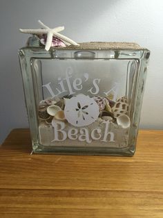 a glass block with shells and starfish in it that says life's a beach