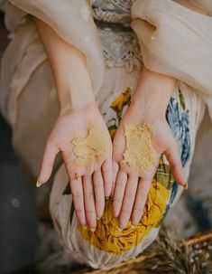 a woman holding out her hands with some yellow powder on it