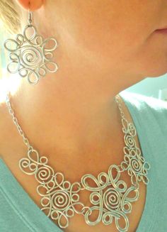 a woman wearing a necklace made out of silver filigrees on her neck