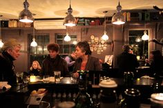 three people sitting at a table in a restaurant with bottles and glasses on the counter