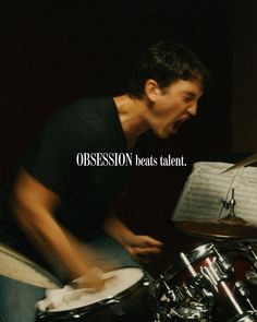 a man that is sitting in front of a drum set and has his mouth open