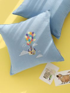 two blue pillows sitting on top of a yellow table next to pictures and a dog