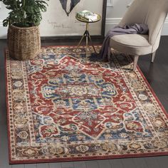 a red rug with blue and gold designs on it in front of a white chair