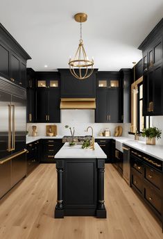 a kitchen with black cabinets and white counter tops, gold accents on the doors, and a chandelier hanging from the ceiling