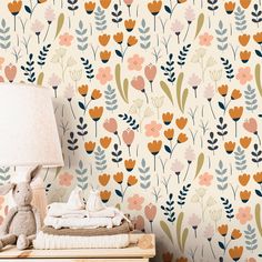 a wallpapered with flowers and leaves is next to a lamp on a dresser