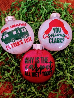 three christmas ornaments sitting on top of some green grass with words painted on them and an ornament that says, why is the coldest all wet tour?