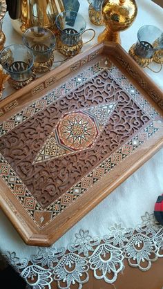 an ornate wooden tray on a table with lace and other decorative items around the edges