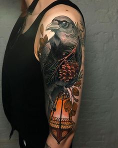 a woman's arm with a bird and pine cone tattoo on it