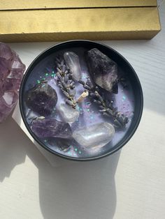 a bowl filled with rocks and crystals next to a golden box on top of a table