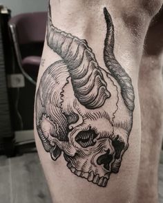 a man's leg with a skull and horns tattoo on it