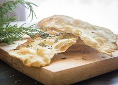 a wooden cutting board topped with chips and a sprig of rosemary next to it