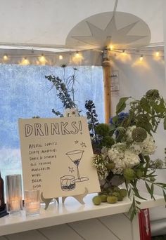 there is a sign that says drinks and flowers on the table in front of it