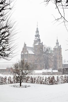 a large building sitting on top of a snow covered field next to trees and bushes