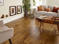 a living room with wood floors and white furniture, including a gray couch and coffee table