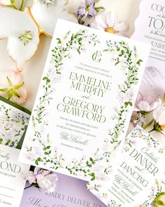 the wedding stationery is laid out on top of each other, with flowers and greenery