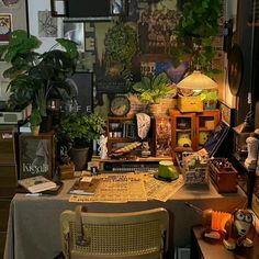 a desk with many plants and pictures on the wall above it, along with other items