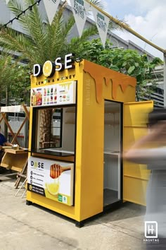 a yellow food cart sitting on the side of a road next to a palm tree