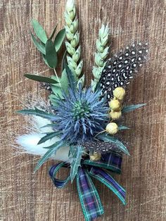 an arrangement of flowers and feathers on a wooden surface