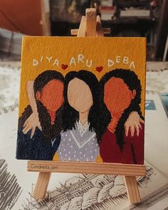 an easel with a painting of three women on it and the words dyaaru deba