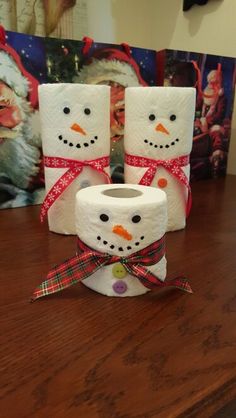 three toilet paper snowmen sitting on top of a wooden table