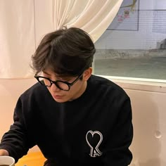 a young man sitting at a table with a plate of food in front of him