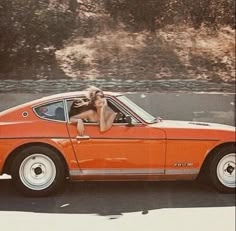 a woman sitting in the drivers seat of an orange car