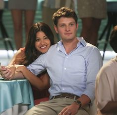 a man and woman sitting next to each other in front of a blue table cloth