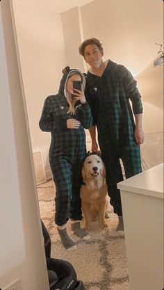 a man and woman in pajamas standing next to a golden retriever dog on the floor