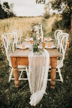 an outdoor table set up with white chairs