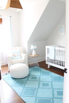 a baby's room with a white crib and blue rug