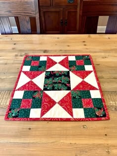 a red and green quilted placemat on a wooden table