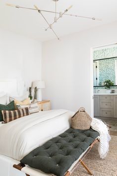 a white bed sitting next to a window with lots of pillows on top of it