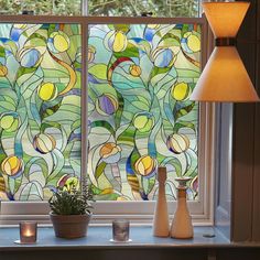 a stained glass window with two vases next to it and a lamp on the side