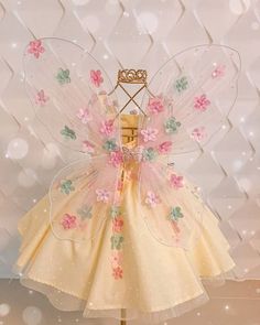 a yellow dress with pink flowers on it and a tiara hanging from the back